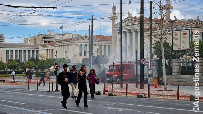 XIX a. Atėnų didingi pastatai. Priekyje rūksta dūmai - anarchistai padegė šiukšliadėžes protesto metu, ugniagesiai gesina