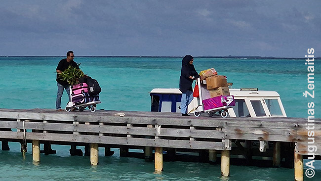 Žmonės atplaukė į Hanimadū salą, prisišvartavo laiveliu prie oro uosto, ir su daiktais eina į lėktuvą